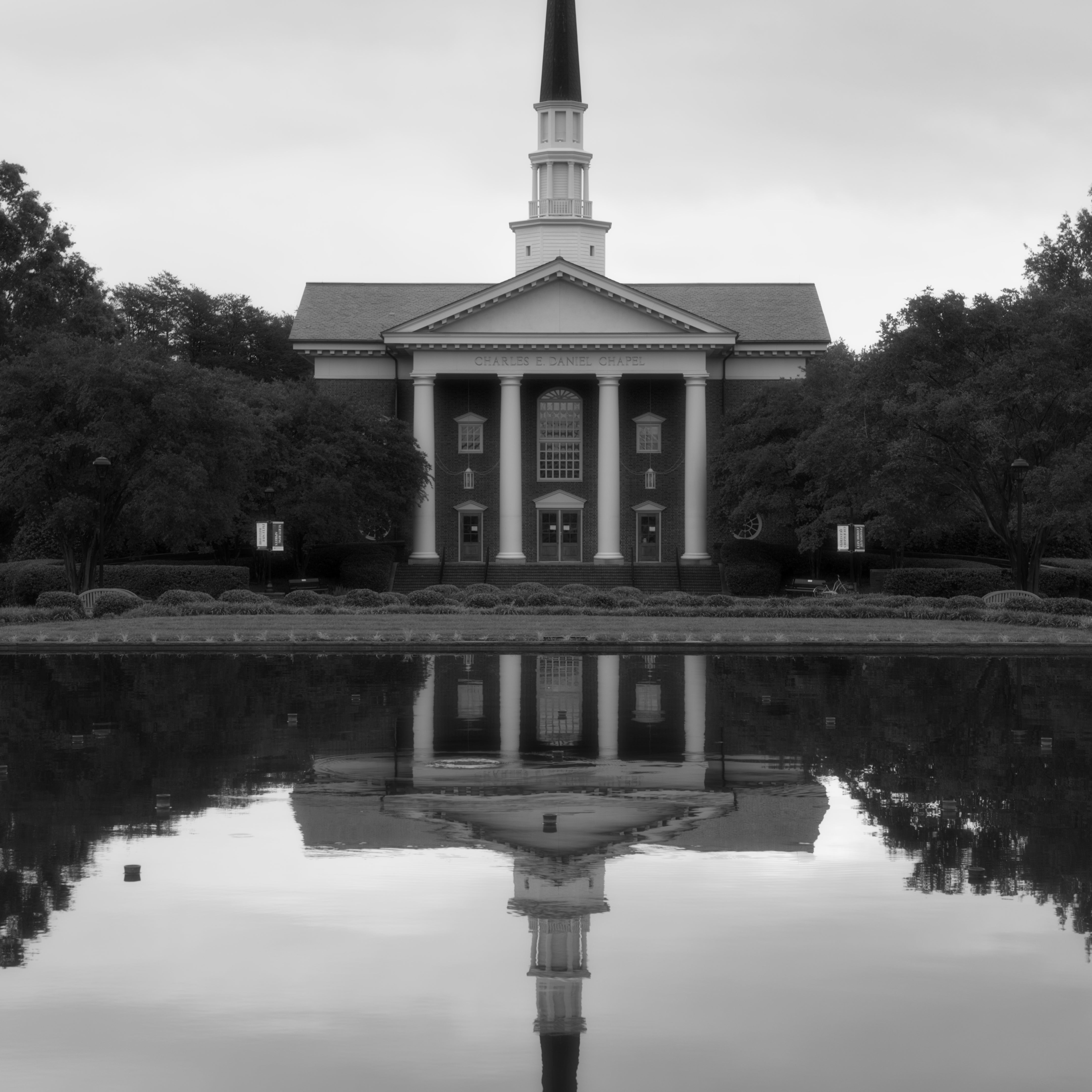 A tall image in black and white of a chapel at Furman University and it's reflection in the fountain water
