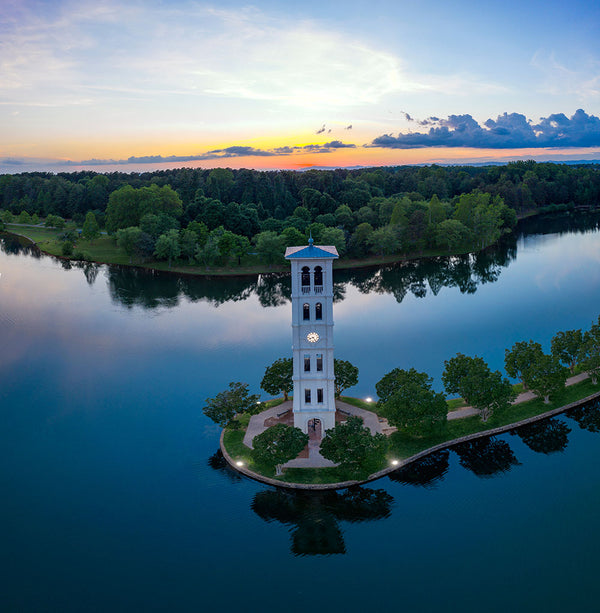 An aerial view of the bell tower at Furman University, with the sun setting in the background