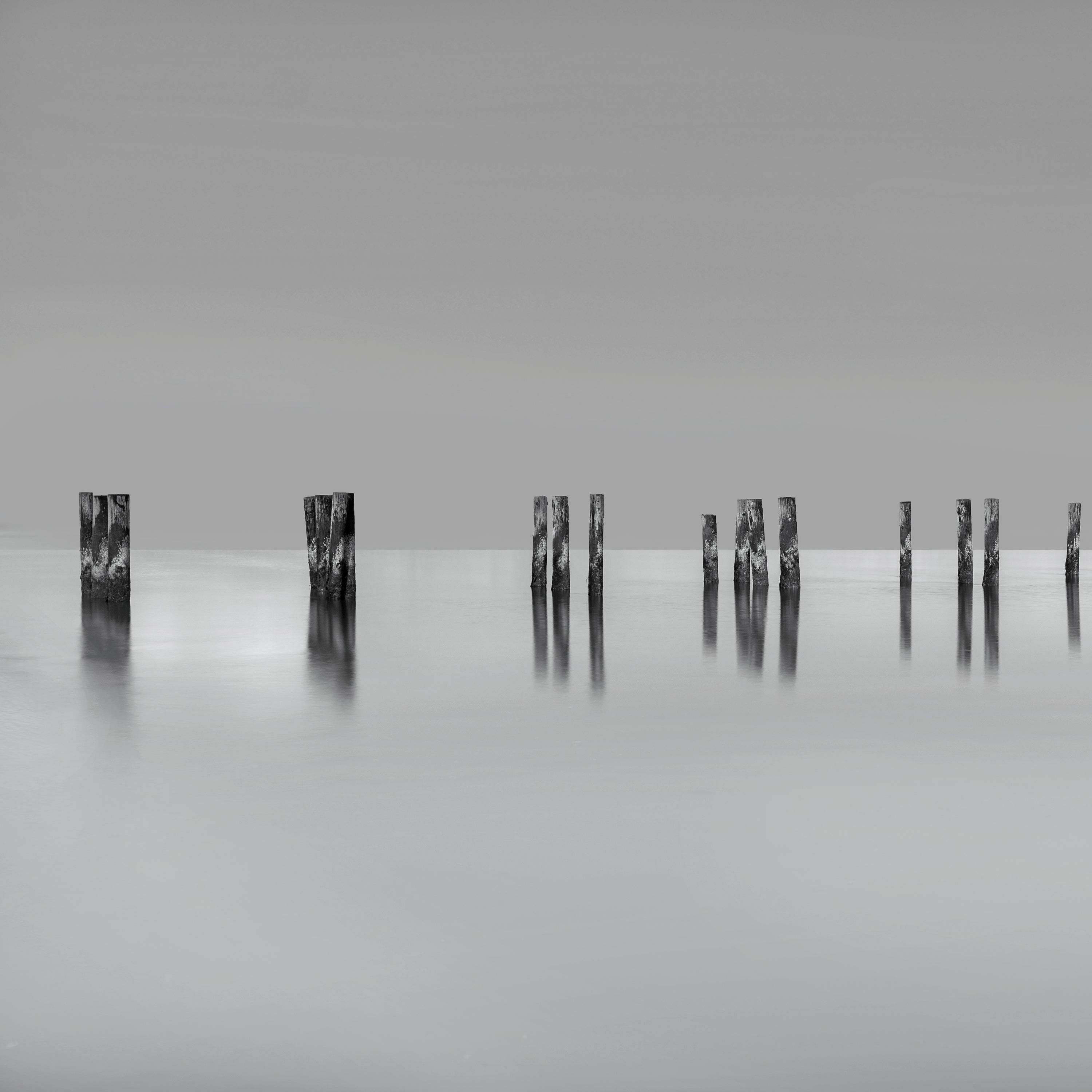Posts stemming from the water about 3 feet up.  The posts are textured and striped.  The image is long exposure fine art.